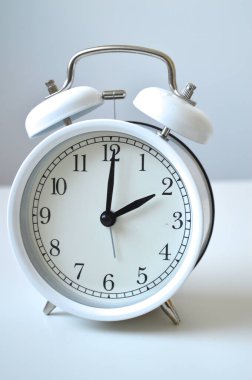 Zaman yönetimi kavramını gösteren beyaz çerçeveli klasik ikiz çan çalar saati. İşletme, verimlilik ve temiz estetik ile zamana bağlı içerik için mükemmel..