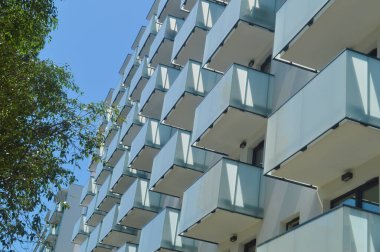 Düşük açılı çarpıcı bir görüntü, Varşova 'daki çağdaş bir apartmanda cam balkonların tekrarlanan şablonlarını yakalıyor. Bu resim kentteki modern mimari, kentsel konut tasarımı ve yeni konut gelişimlerini vurgular..