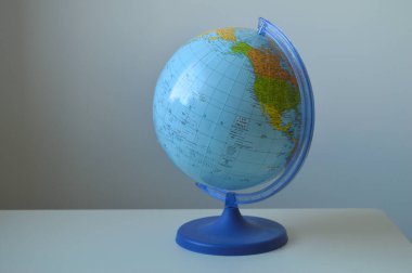 Kıtaları ve ulusal sınırları açıkça gösteren canlı, mavi bir siyasi küre, basit bir arkaplana karşı duruyor. Bu resim küresel çalışmalar, seyahat, eğitim, haritacılık ve uluslararası ilişkileri sembolize etmektedir.