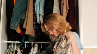 Kız elbiseleri deniyor. Mutlu duygular. Randevudan önce seçim yap. Dolabın kapısını açar. Beyaz parlak iç döşeme.