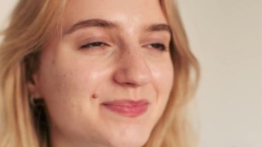 Kahverengi gözlü güzel, sarışın bir kız kameraya gülümsüyor. Güzel cilt. Eğlenmene bak..