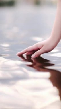 Gölde elini tutan bir kadın.