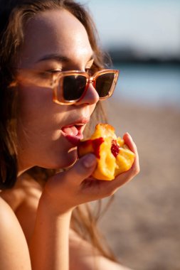 Yaz kumsalında karpuz yiyen bir kadın. Şeftali