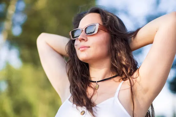 Genç kadın gözlük takıyor ve gülümsüyor.