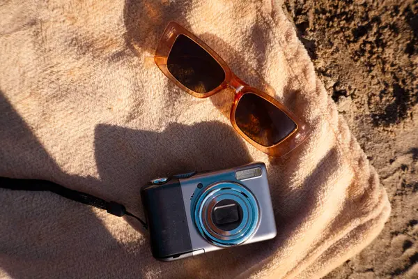 Kamera, gözlük, güneş gözlüğü ve kumsalda kum. Üst görünüm, boşluk kopyala.