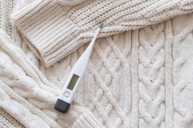 Yatağın üzerinde termometre ve beyaz bir battaniye.