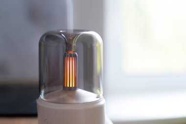 Hava nemlendirici. Aroma lambası. Yağlar. Minimalizm. Hava nemlendirmesi için minimalist lamba. Yatay fotoğraf. Reklam fotoğrafı. Meditasyon. Yanan lamba. Beyaz dava. Kablosuz aroma lambası