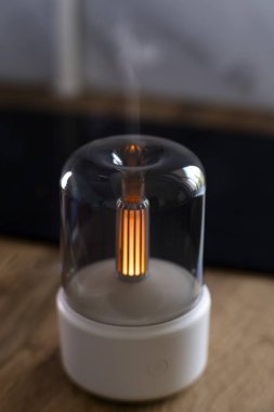 Hava nemlendirici. Aroma lambası. Yağlar. Minimalizm. Hava nemlendirmesi için minimalist lamba. Yatay fotoğraf. Reklam fotoğrafı. Meditasyon. Yanan lamba. Beyaz dava. Kablosuz aroma lambası