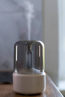 Hava nemlendirici. Aroma lambası. Yağlar. Minimalizm. Hava nemlendirmesi için minimalist lamba. Yatay fotoğraf. Reklam fotoğrafı. Meditasyon. Yanan lamba. Beyaz dava. Kablosuz aroma lambası