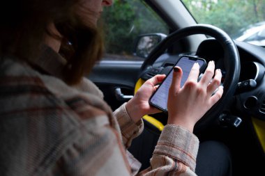 Araba kullanırken akıllı telefon kullanan kadın