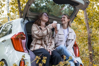 Sonbahar ormanında bir fincan kahveyle mutlu genç bir kadın. sonbahar seyahati. 