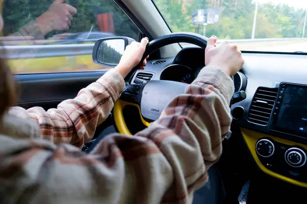 Araba süren genç bir kadın. Direksiyon tutarken