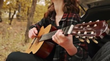 Doğada akustik gitar çalan bir kız.