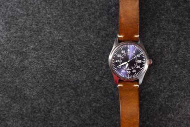 Deri kayışlı bir kol saati. Mekanik saat. Kahverengi kayış. Mor düğme. Erkek aksesuarı. Karanlık arka plan. Ürün çekimi