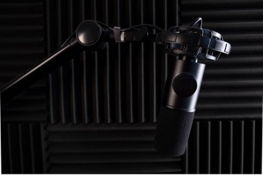 Stüdyo ses kaydı için mikrofon. Stüdyo. Yüksek kaliteli ses. Ses geçirmez. Siyah mikrofon. Stüdyo mikrofonu. Podcast. Telsiz. Minimalist tasarım. Karanlık arka plan. Karbon gövde