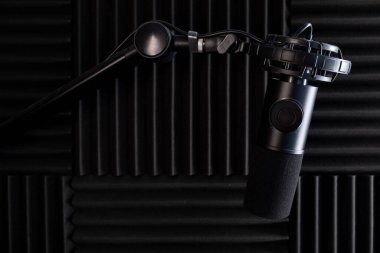 Stüdyo ses kaydı için mikrofon. Stüdyo. Yüksek kaliteli ses. Ses geçirmez. Siyah mikrofon. Stüdyo mikrofonu. Podcast. Telsiz. Minimalist tasarım. Karanlık arka plan. Karbon gövde