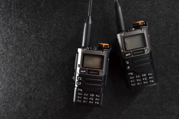 Radyo sistemi. Walkie-talkie. İki tane telsiz. Anten. Walkie-talkie 'nin elinde. Gri arka plan. Minimalizm. Ürün fotoğrafı. Fotoğraf kalitesi iyi