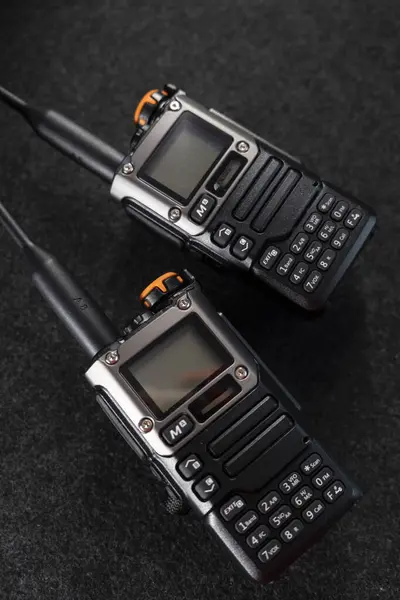 Radyo sistemi. Walkie-talkie. İki tane telsiz. Anten. Walkie-talkie 'nin elinde. Gri arka plan. Minimalizm. Ürün fotoğrafı. Fotoğraf kalitesi iyi