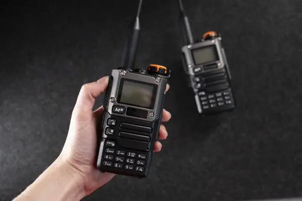 Radyo sistemi. Walkie-talkie. İki tane telsiz. Anten. Walkie-talkie 'nin elinde. Gri arka plan. Minimalizm. Ürün fotoğrafı. Fotoğraf kalitesi iyi