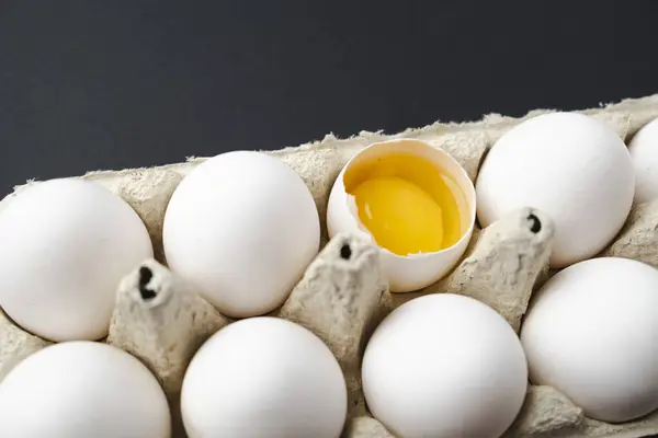 Renkli kahverengi yumurtalarla dolu bir kutu, bir açık yumurta sarısı, dikdörtgen yumurta kartonunda gri beton arka plan. Paskalya yumurtaları. Doğrudan yukarıdan ateş edilmiş. Yüksek kalite fotoğraf