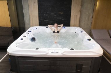 Kollarında havluyla beyaz bornozlu genç bir kadın. jakuzi