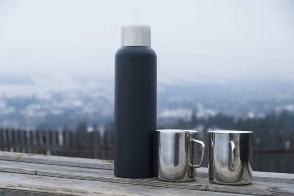 Dağların arkasındaki ahşap bir masada termos..