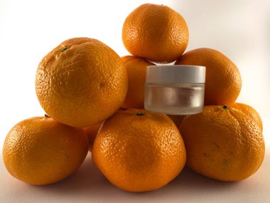 Portakalları cilt bakım kremi kavanozunun yanına istifleyin. Krema kavanozu modeli.