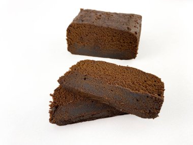 Koyu ve nemli bir pastanın birkaç diliminin yakın planında zengin ve parçalanmış bir doku var. Pasta beyaz bir arkaplanda düzenleniyor. Kek. Düz açılı kek.