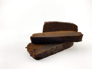 Koyu ve nemli bir pastanın birkaç diliminin yakın planında zengin ve parçalanmış bir doku var. Pasta beyaz bir arkaplanda düzenleniyor. Kek. Düz açılı kek.