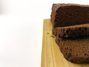 Ahşap bir kesme tahtasının üzerinde iki tane çökmüş browninin yakın plan görüntüsü. Browni zengin, çikolatalı bir dokuya sahip ve tatlı bir dokunuş için pudra şekerle kaplanmış. Ağzını sulandıran bir browni.