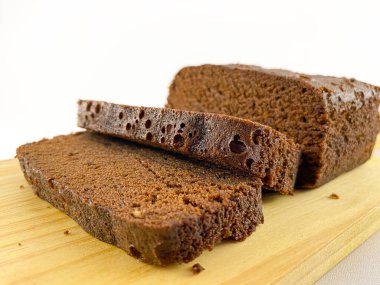 Ahşap bir kesme tahtasının üzerinde iki tane çökmüş browninin yakın plan görüntüsü. Browni zengin, çikolatalı bir dokuya sahip ve tatlı bir dokunuş için pudra şekerle kaplanmış. Ağzını sulandıran bir browni.