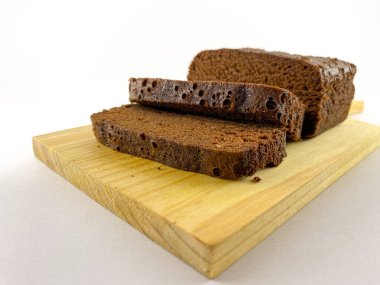 Ahşap bir kesme tahtasının üzerinde iki tane çökmüş browninin yakın plan görüntüsü. Browni zengin, çikolatalı bir dokuya sahip ve tatlı bir dokunuş için pudra şekerle kaplanmış. Ağzını sulandıran bir browni.
