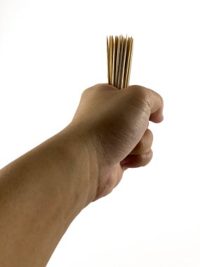 Bir insanın elinde tutulan bir avuç tahta kürdan. Kürdanlar üst kısımları yukarıya bakan bir deste halinde dizilmiş. El kürdanları rahat bir şekilde tutuyor..