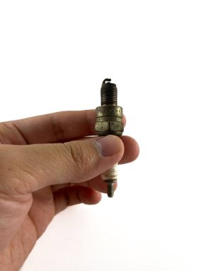 Buji tutan bir el. Buji, hava-yakıt karışımını içten yanmalı motorda ateşlemek için kullanılan küçük, silindirik bir cihaz..
