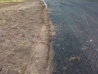 Taze asfalt üst görünümü. Yakın planda yarım asfaltlı bir yol. Yol yapımı. Arka plan, metin için yer, doku. Yeni ve eski yollar.