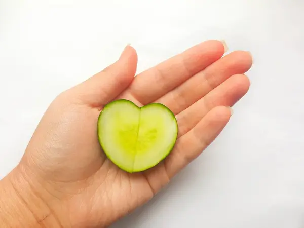 Avucunun içinde kalp şeklinde dilimlenmiş salatalık. Yemek pişirme sevgisi kavramı. Düzgün beslenme ve diyet kavramı. Arka plan, mesaj için yer. Vejetaryenlik, vejetaryenlik.