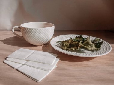 Masanın üzerinde bir kupa çay ve kurutulmuş bitkiler. Kahvaltıda. Sabah kahvesi. Arka plan, mesaj için yer. Bitkisel çay faydaları ve zararları.