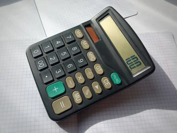 stock image The calculator is lying on a notebook in a cage on the table. The number 100 on the calculator. Mortgage. Loans. Price increase. Lower prices.