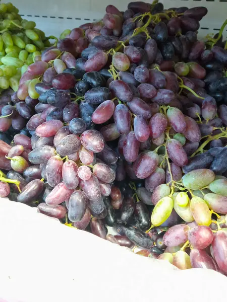 Süpermarketin vitrinindeki bir kutuda üzüm. Markette koyu üzüm bağları var. Market alışverişi. Geçmişi. Metin için bir yer.