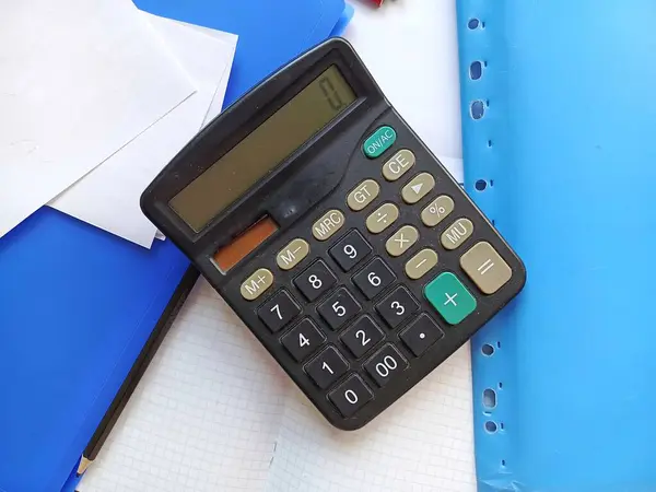 Masanın üzerinde bir hesap makinesi, klasörler, not defteri ve kağıtlar var. Maaş, sosyal yardım ve emekli maaşı kavramı. 