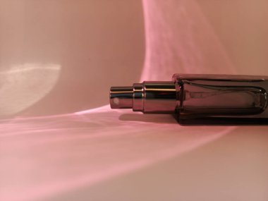 Parfüm şişesini aç. Pembe dumanlı parfüm şişesi. Parfümün üzerinde pembe ışık parlıyor. Zarif parfüm kokusu. Reklam için arka plan. Metin için boşluk.