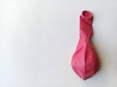 Kırmızı bir balon. Masada sönmüş bir balon, beyaz arka plan. Çocuklar için oyuncaklar. Metin için arkaplan, boşluk.