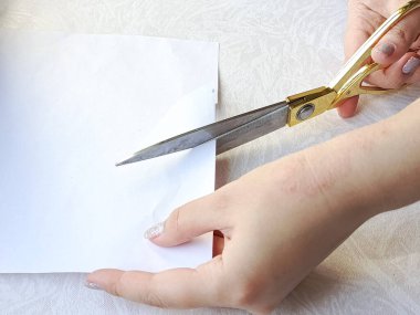 Elleri makasla kesilmiş kağıt. Makas beyaz bir sayfa kağıt kesti. Arka plan, mesaj için yer. Okul konsepti için çocuk başvuruları. Çocuk işi..