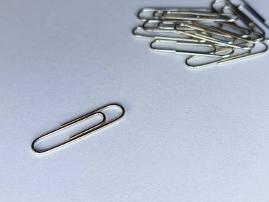 Masanın üzerinde bir ataç var, arka planda bir yığın metal ataç var. Reklam arkaplanı, metin için boşluk. Kırtasiye malzemeleri. Ofis malzemeleri.