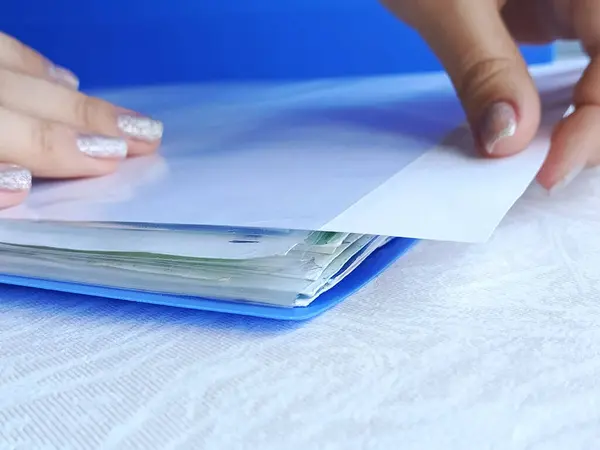 Bir kadın klasördeki bir dosyadan beyaz bir kağıt alıyor. Nüfus sayımı, belge kaydı kavramı. Kredi, ipotek. Metin için arkaplan, boşluk.