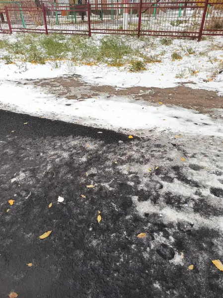 Çitin yanında ince bir beyaz kar tabakası uzanıyor. İlk yağan kar. Geçerli bir hava. Çok soğuk. Soğuk kasırga. Kar şeklinde yağış. Arkaplan.