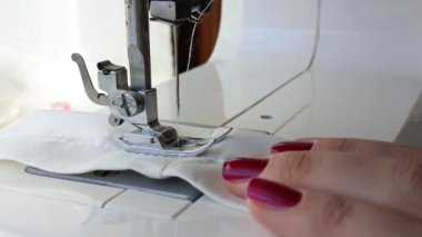 Eller dikiş makinesinin ayağını kaldırıyor. Kadın terzi dikiş dikmeyi bitirdi. Dikiş dikmek. Elbise dikiyorum. Atıcısın. Geçmişi. Giysi tamiri.