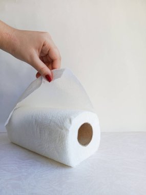 A woman's hand tears a paper towel from a roll. Roll of disposable paper towels made of virgin cellulose. Hygiene. Background, space for text. personal hygiene, hand hygiene. clipart