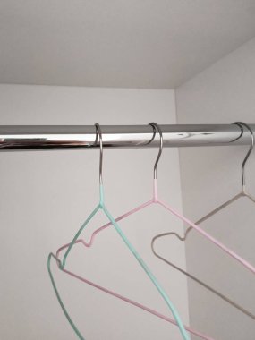 Clothes hangers are hanging in an empty closet. Storage, organization of the cabinet. The background for the advertisement, the place for the text. Wardrobe.  clipart