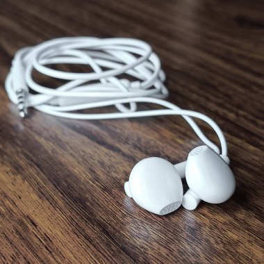 Beyaz kablo kulaklıklar yakın planda masanın üzerinde duruyor. Telefona kulaklık. Metin için arkaplan, yer. 